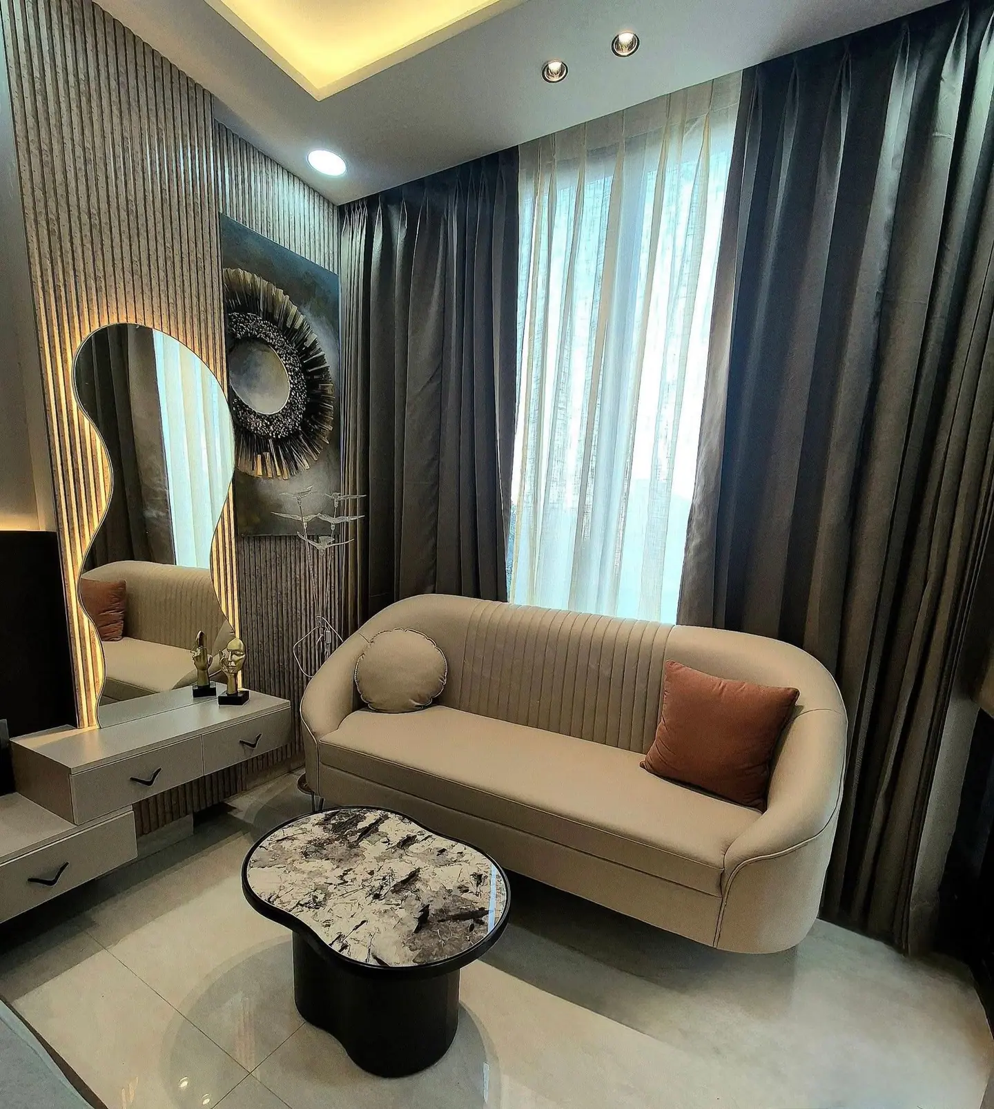 Lounge corner with a curved sofa, fluted wall panels and a sculpted mirror